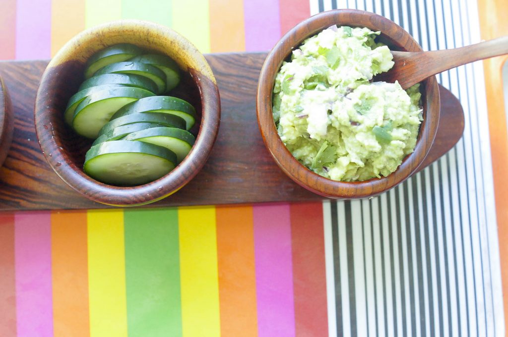 Guacamole in bowl next to cucumbers